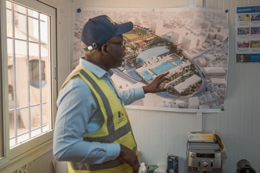 Babacar Senghor, coordinator of the Youth Olympic Games project (YOG), standing before pool plans.
