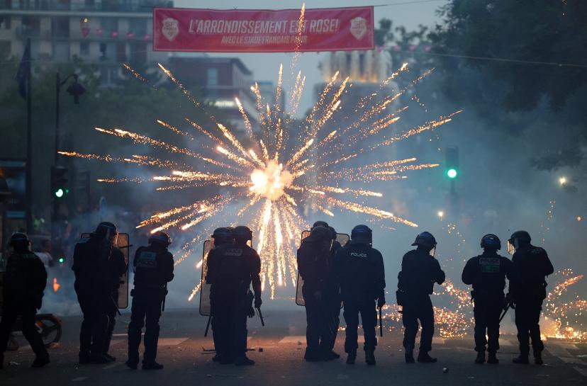 Fireworks light up the sky as police maintain order in Paris after PSG's Champions League victory.