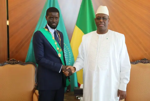 Newly elected Senegalese President Bassirou Diomaye Faye (left) shakes hands with former Senegalese President Macky Sall (right) during a photo session after taking the oath before the Constitutional Council, following the investiture ceremony in Dakar, Senegal, on April 2, 2024.