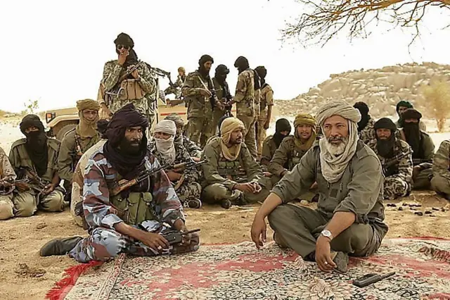 Touareg rebels gathered under a tree with armed fighters