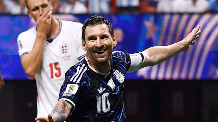 Lionel Messi smiles while an opponent looks dejected