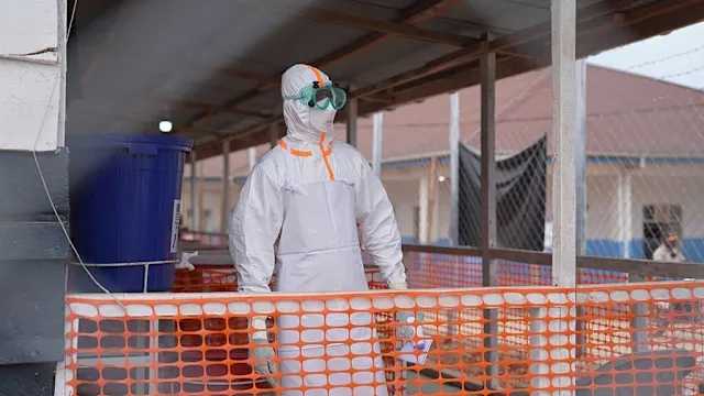 Health workers in protective gear attending to a patient in an Ebola treatment center